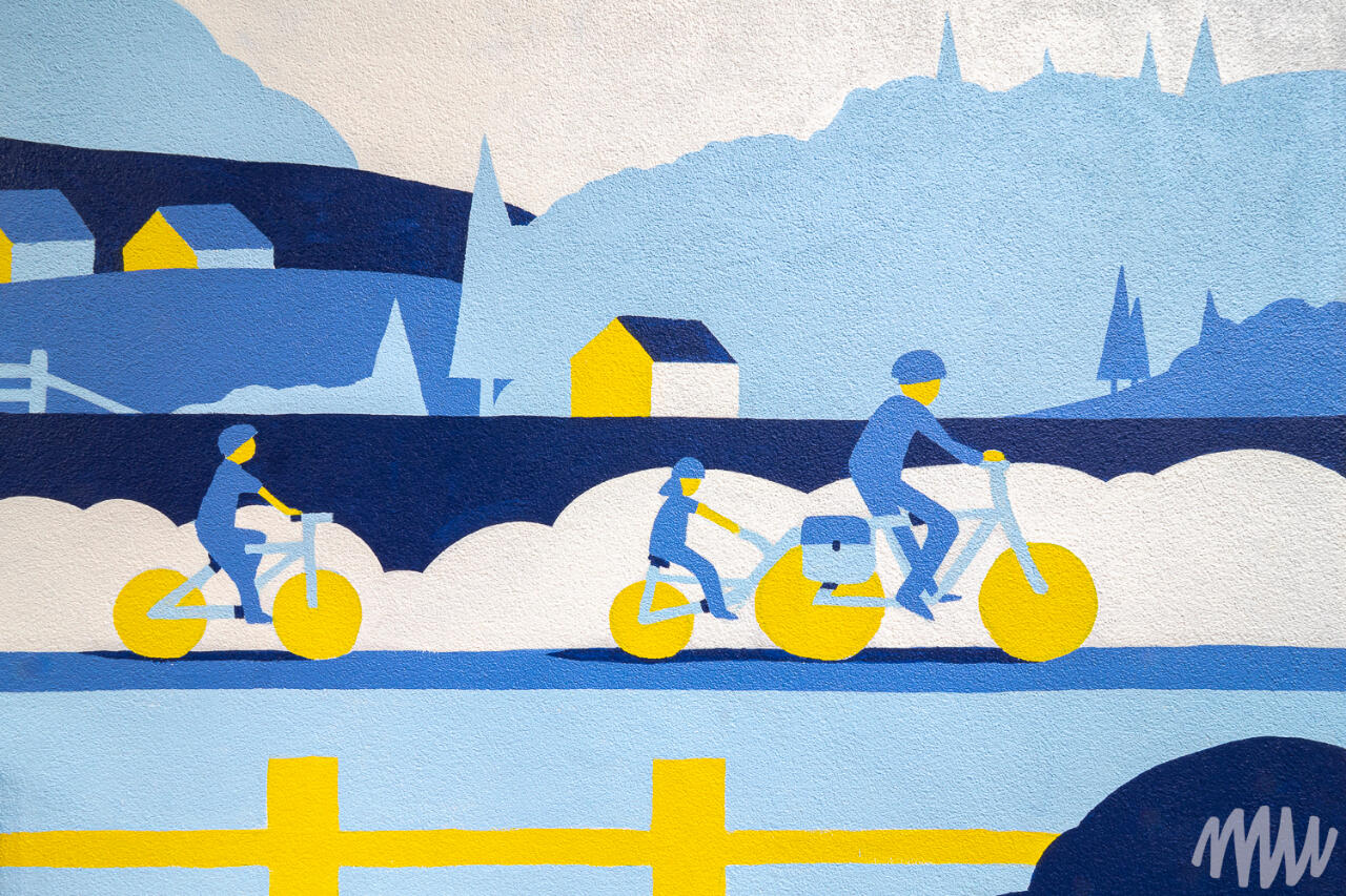 Un détail de la murale, représentant une famille à vélo devant un paysage.