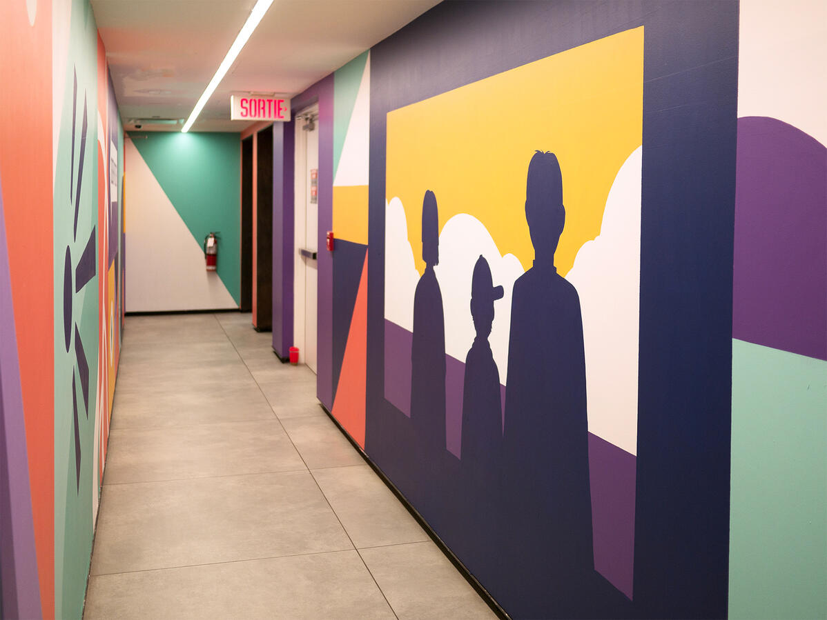 Une murale peinte dans le couloirs vers l'observatoire de la place Ville-Marie par Lucas Saenger. Une composition en blocs de couleurs représentant des éléments de la ville et des symboles.