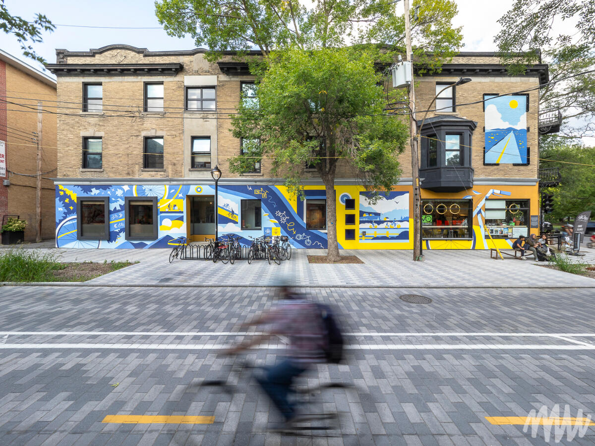 Une murale sur une façade de bâtiment. Le tout représente le vélo sous ses différentes facettes.