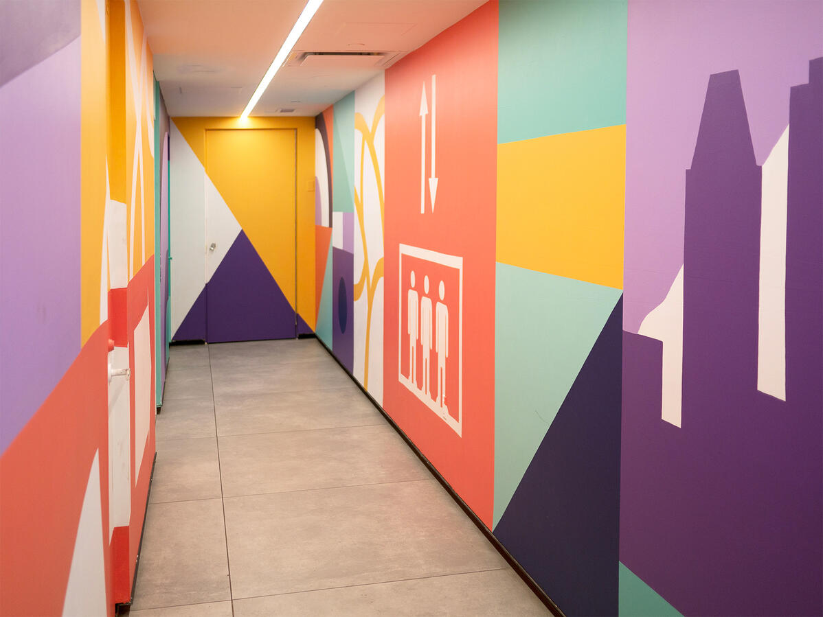 Une murale peinte dans le couloirs vers l'observatoire de la place Ville-Marie par Lucas Saenger. Une composition en blocs de couleurs représentant des éléments de la ville et des symboles.