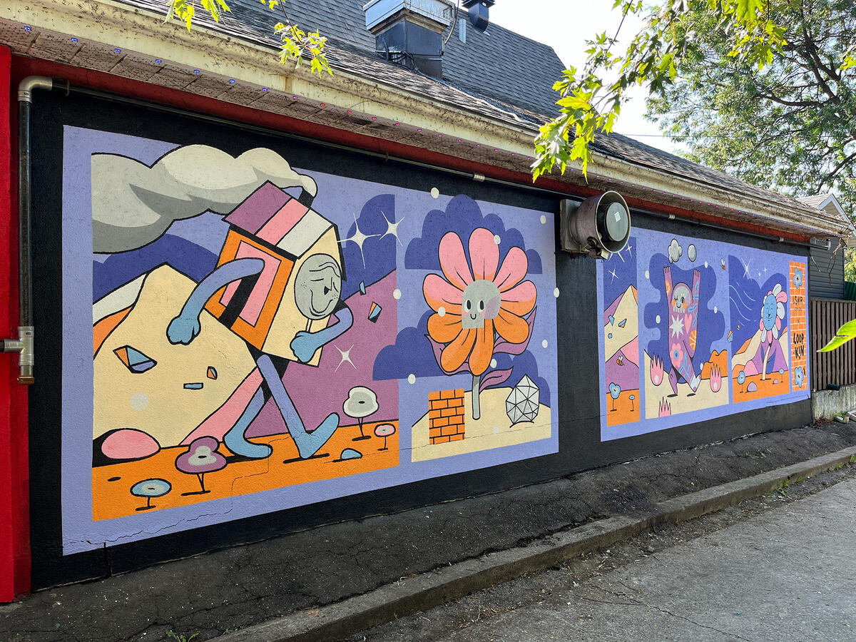 Murale par les artistes Lucas Saenger et Loopkin sur le mur du restaurant Patate Rouge. On y voit des personnages joyeux et colorés en forme de fleurs et de maisons.
