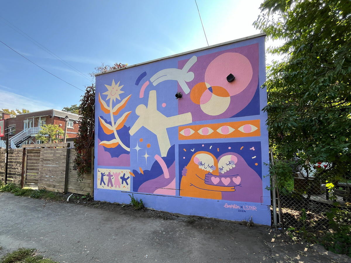 Murale par les artistes Lucas Saenger et Loopkin sur le mur du restaurant Patate Rouge. On y voit des personnages joyeux et colorés en forme de fleurs et de maisons.