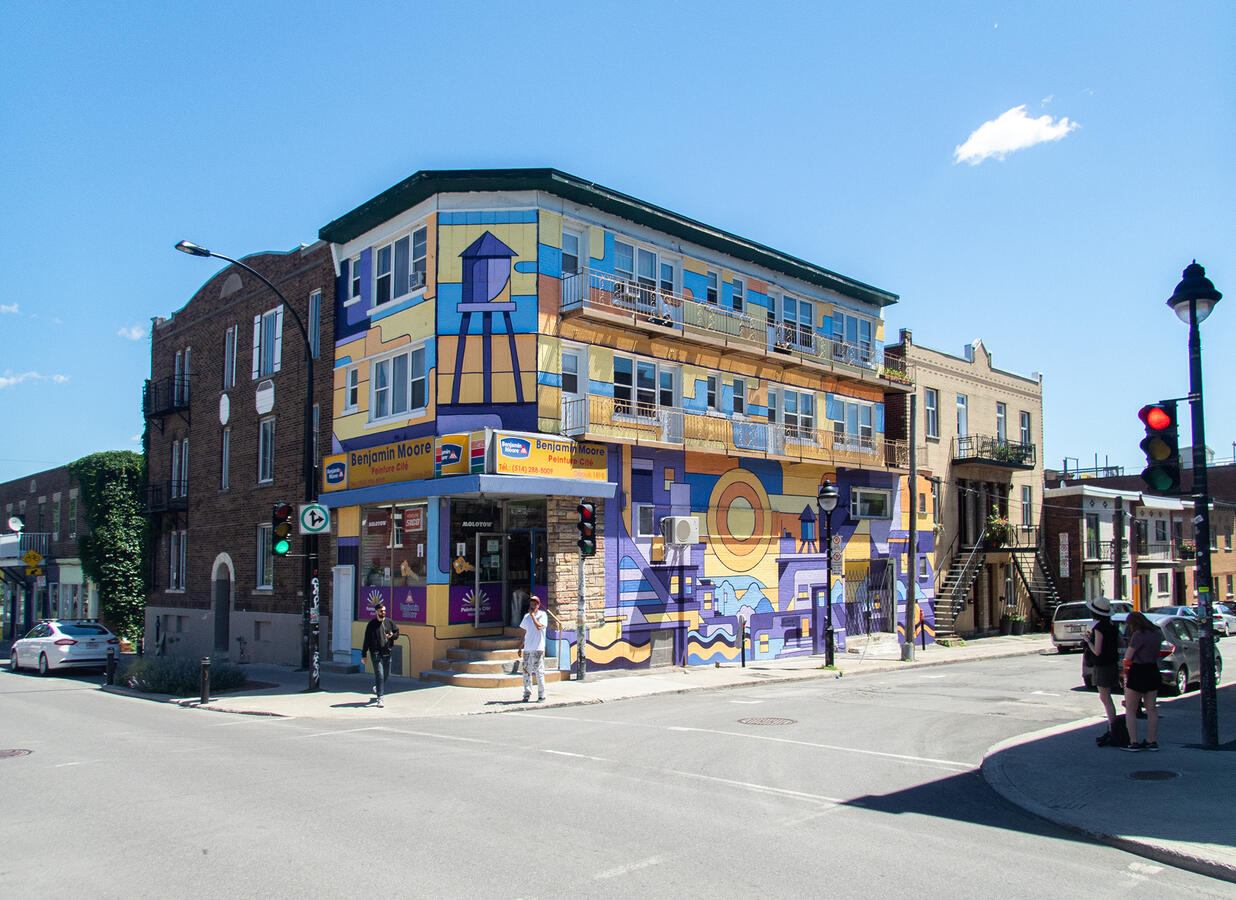 Un bâtiment peint au complet par l'artiste Lucas Saenger. Dans des teintes oranges et bleues, on y voit une représentation graphique de la ville de Montréal.